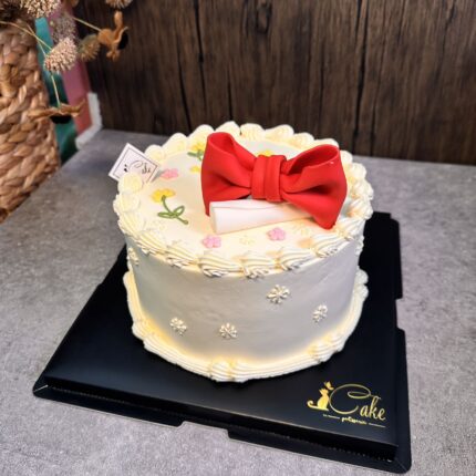 Adorn Your Celebrations with Our Cake Featuring a Stunning Red Bow and Dainty Flowers